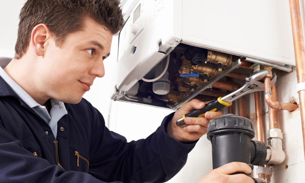 Male Plumber Working On Central Heating Boiler
